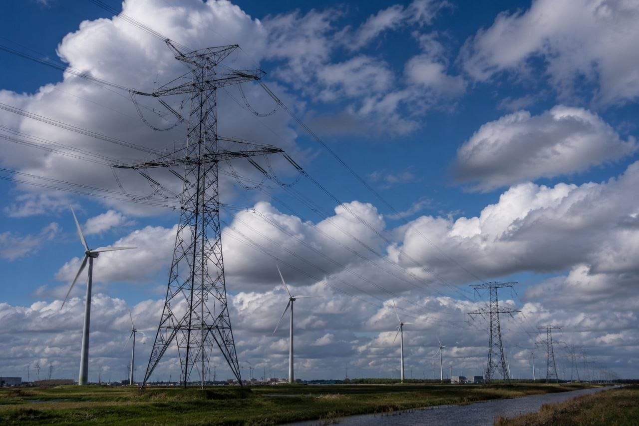Windpark en hoogspanningsmasten in één landschap