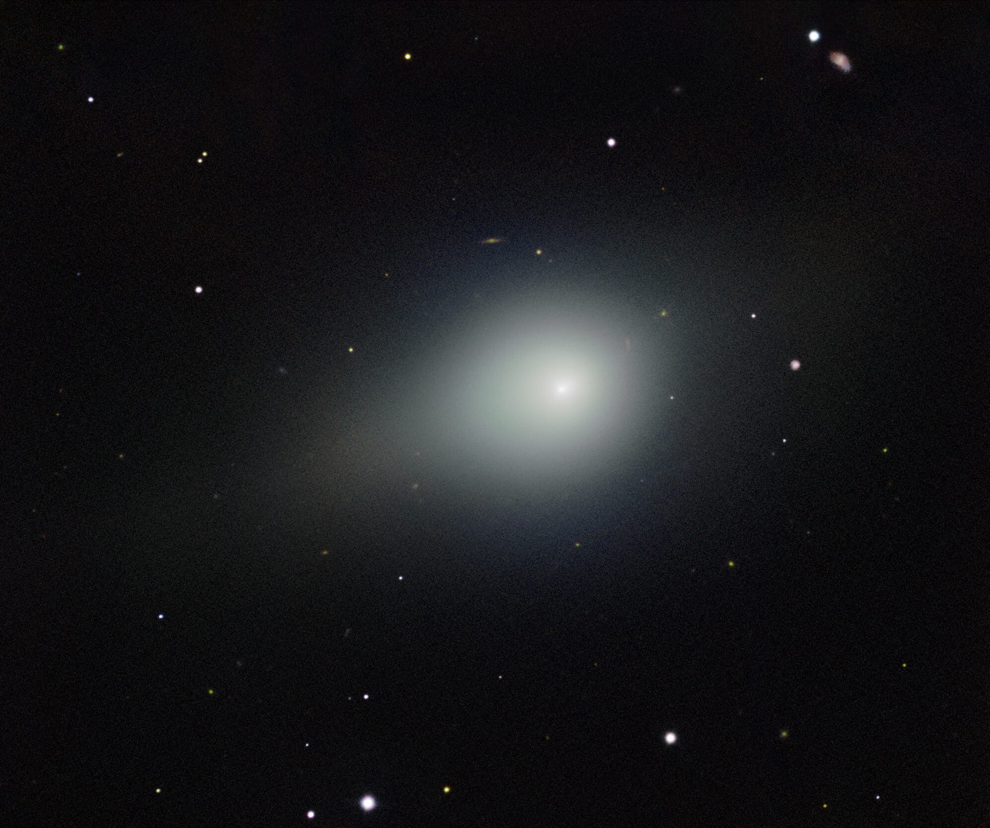 Deep telescope image showing a fuzzy bright coma of comet 3I/ATLAS against a star field, with a faint asteroid smudge visible in the lower right corner.