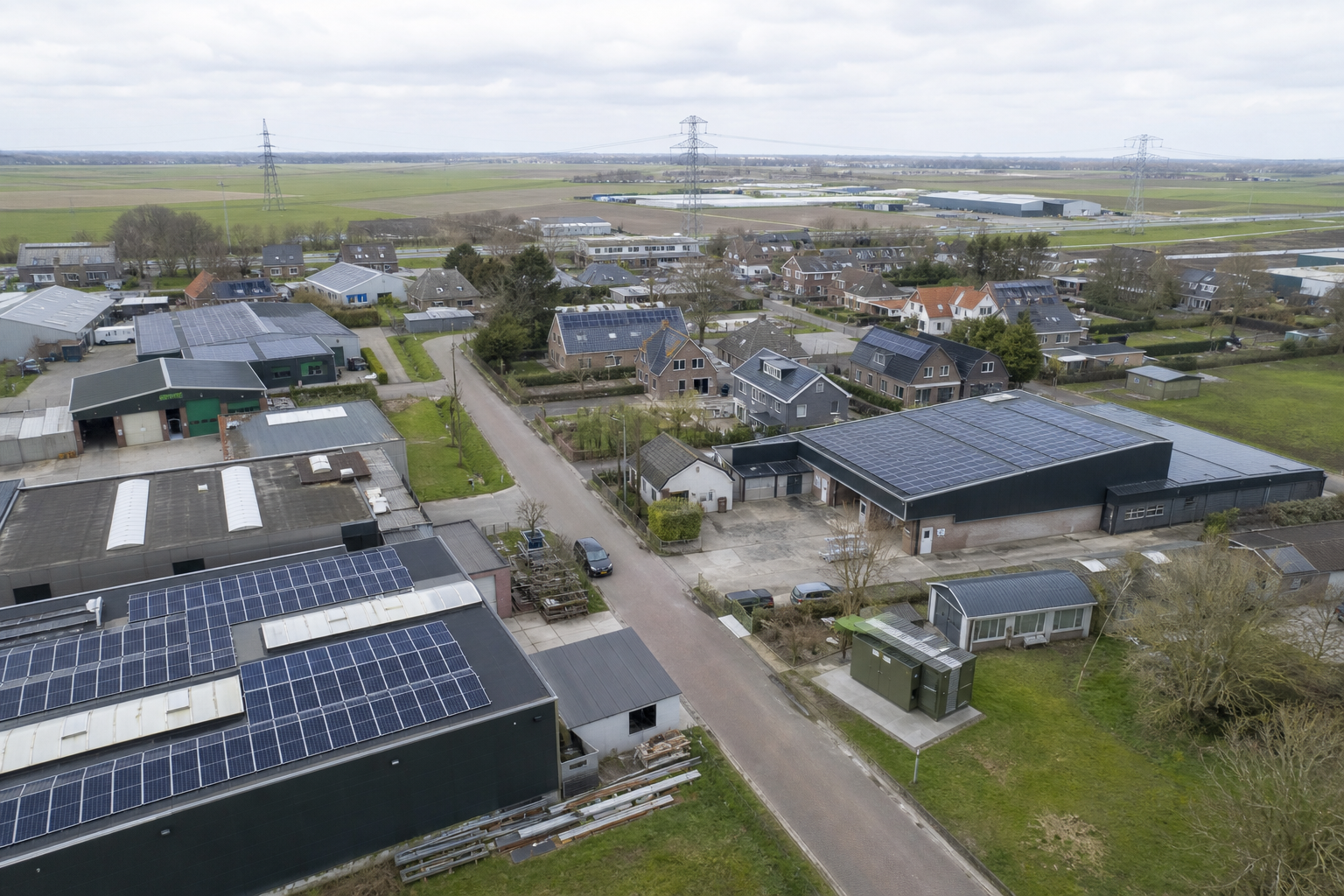 Luchtbeeld van een Nederlandse wijk met kleine bedrijven, woningen, zonnepanelen en zichtbare netinfrastructuur