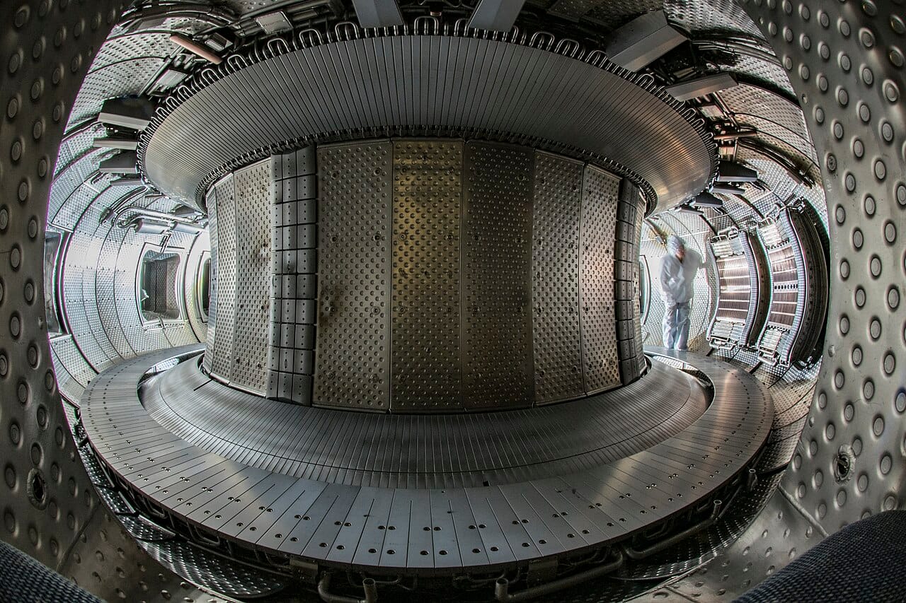 Interior of the WEST tokamak vacuum chamber showing tungsten-armoured wall panels in a circular arrangement at the CEA-IRFM facility in Cadarache, France