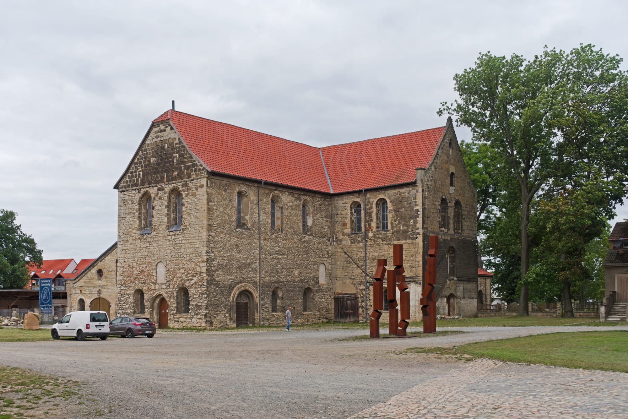 Gothic stone church exterior in Halberstadt with arched entrance, surrounded by bare trees and a fence