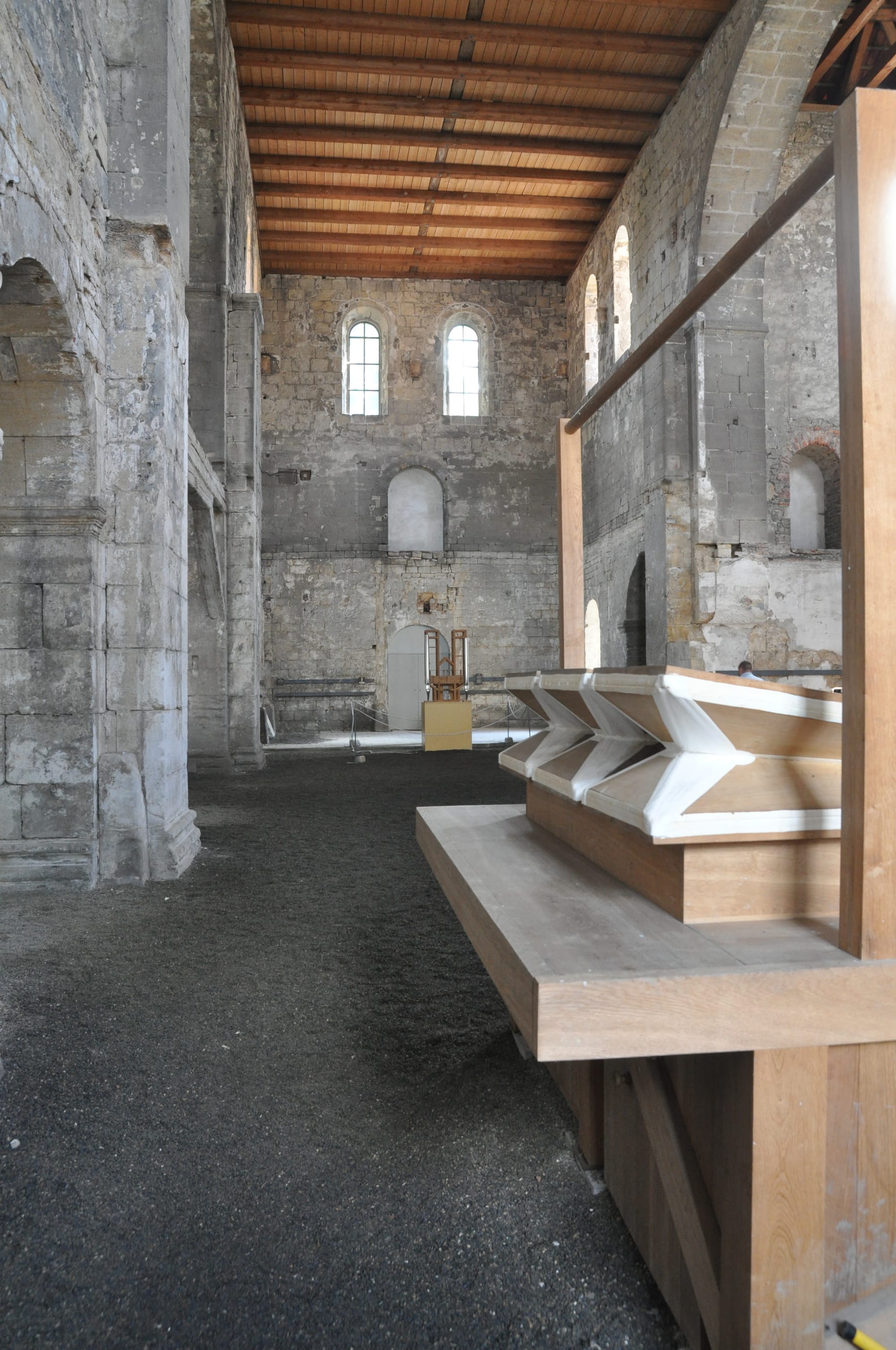 Dark wooden organ bellows inside a stone church, connected by pipes and an electric blower mechanism