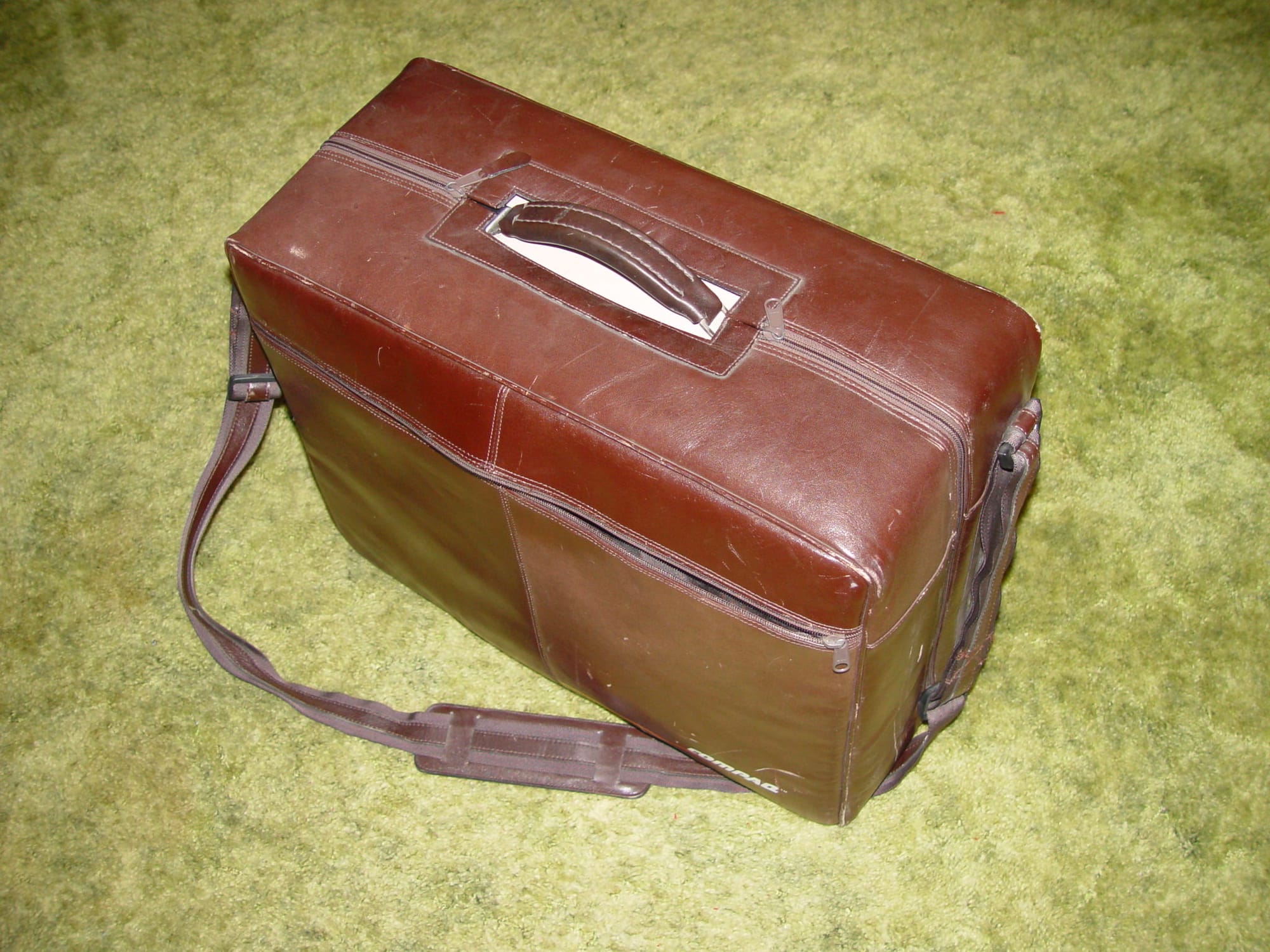 The Compaq Portable (1983), a grey luggable computer with built-in screen and folding keyboard, the first commercially successful IBM-compatible clone