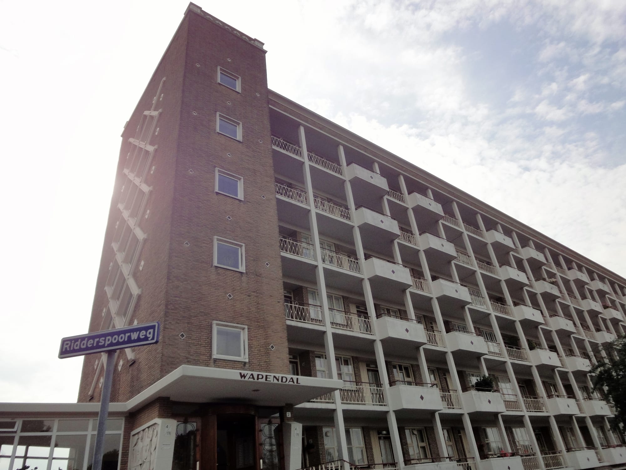 Grijze portiekflat in stedelijke wijk, meerdere verdiepingen hoog, zonder zonnepanelen op het dak