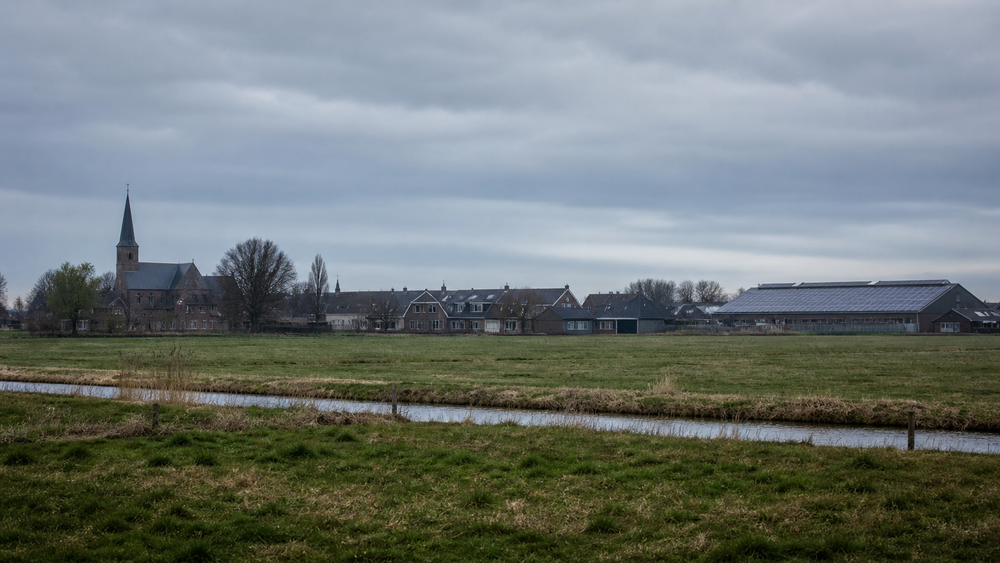 Polder Benthuizen in de vroege ochtend, zonnepanelen op kerk en sportkantine, bewolkte hemel, geen mensen