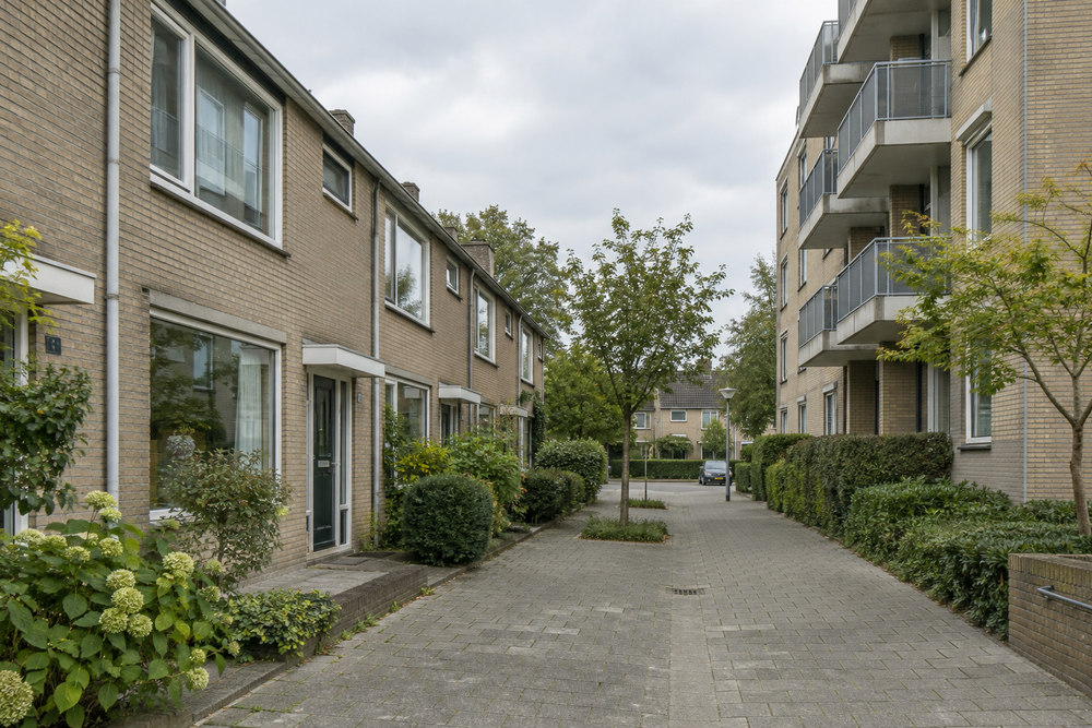 Gestileerde illustratie van ongelijke toegang tot energie in een Nederlandse woonwijk, met contrast tussen zonnepanelen en donkere flats